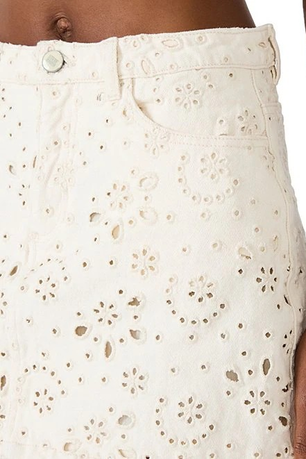 Close-up of a person wearing a white skirt with a subtle pattern.