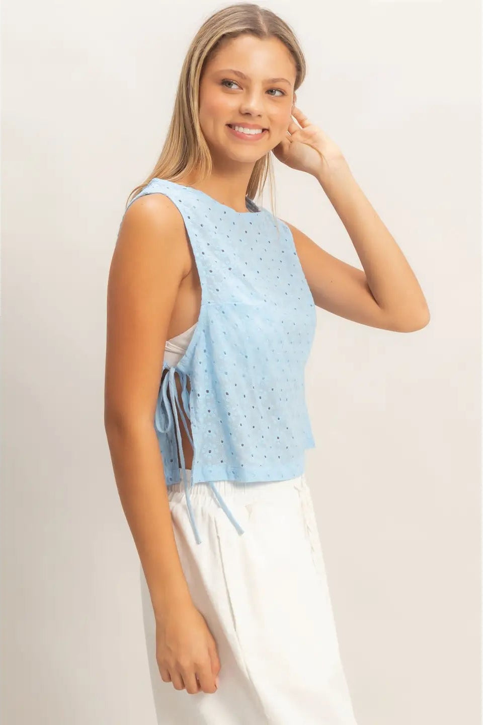 Woman wearing a light blue sleeveless top with a white background