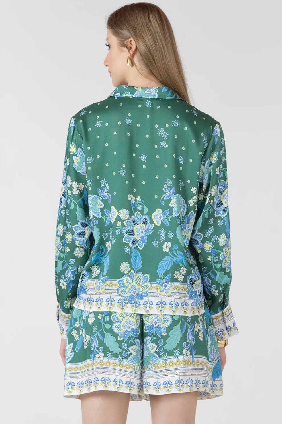 Woman wearing a green floral patterned outfit on a white background