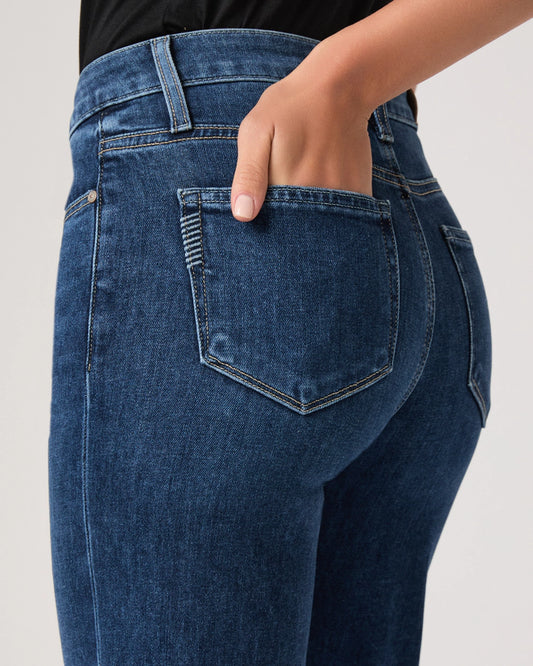 Close-up of blue jeans with a hand in the pocket on a light gray background