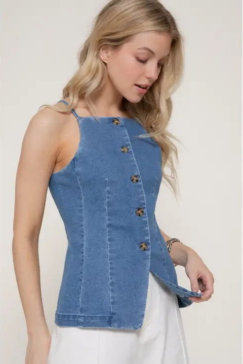 Woman wearing a blue denim top with buttons on a plain background