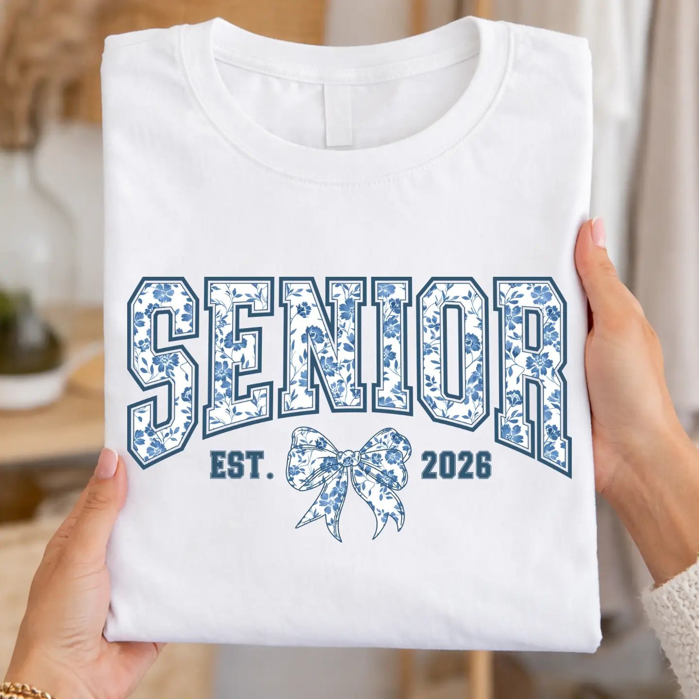 White t-shirt with 'Senior Est. 2026' design held by a person.