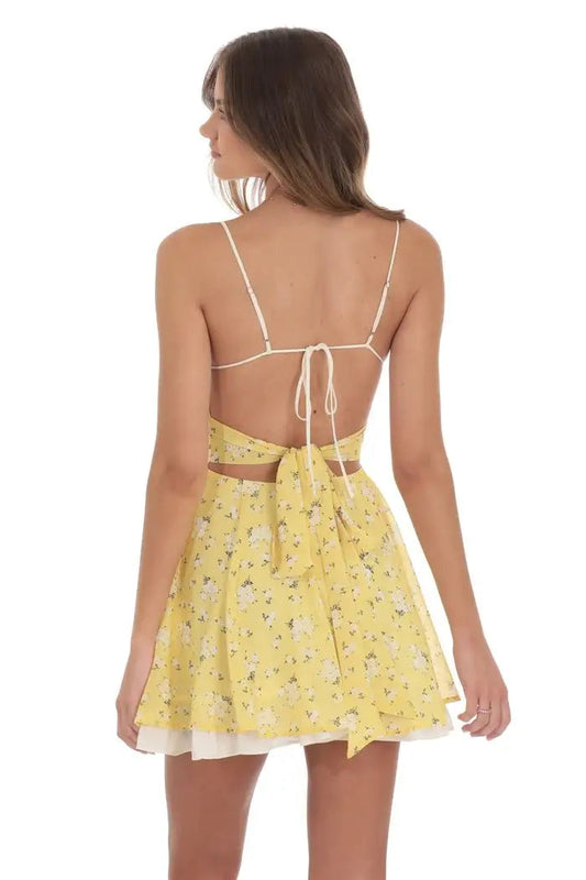 Woman wearing a yellow floral dress with thin straps on a white background