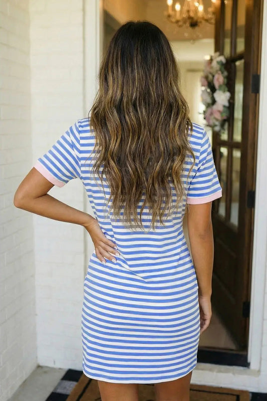 Woman wearing a blue and white striped dress standing in a doorway.