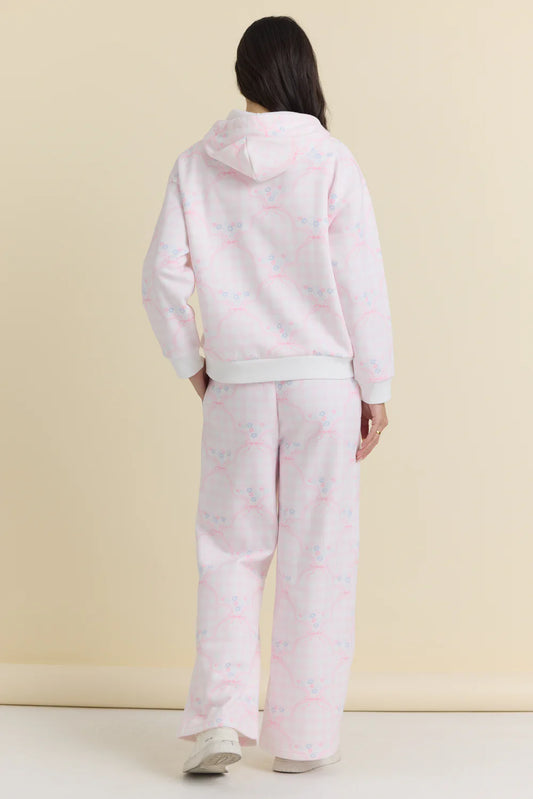 Person wearing a light pink hoodie and pants set on a beige background