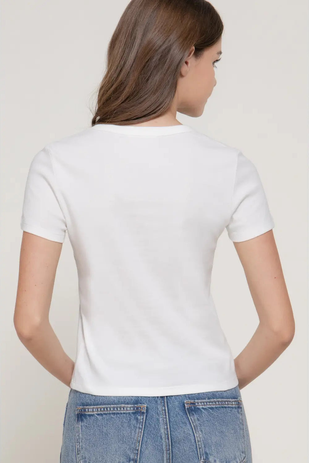 Person wearing a plain white t-shirt and blue jeans against a light background