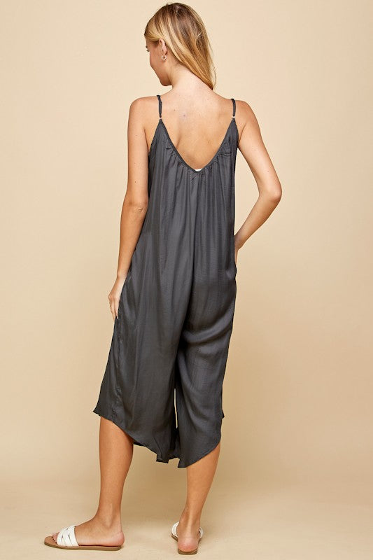 Woman wearing a dark gray slip dress on a beige background