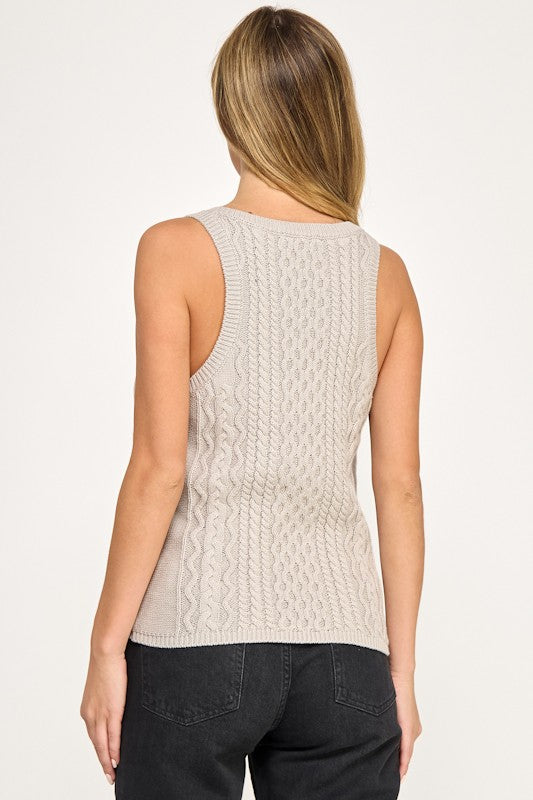 Woman wearing a beige knitted sleeveless top against a white background