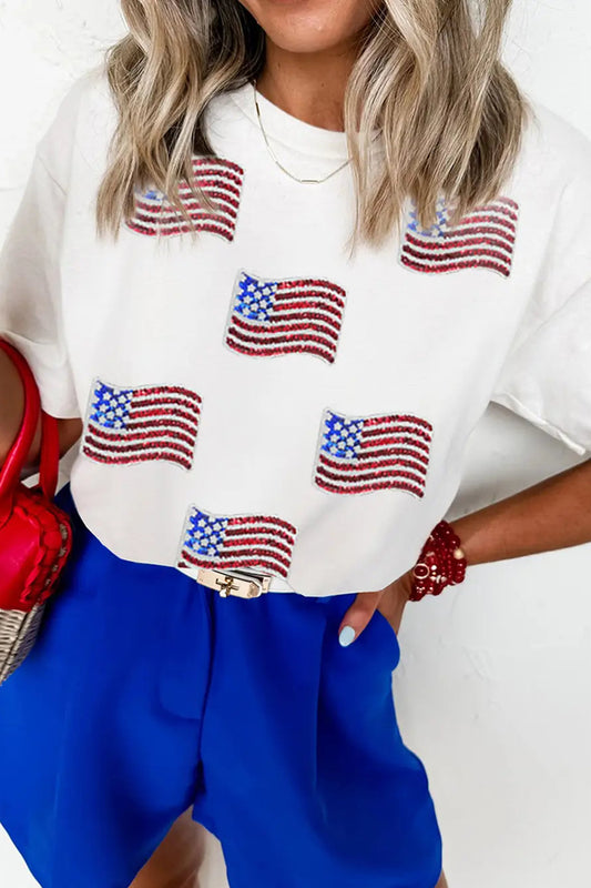 Person wearing a white shirt with American flag patterns and blue pants, holding a red handbag.
