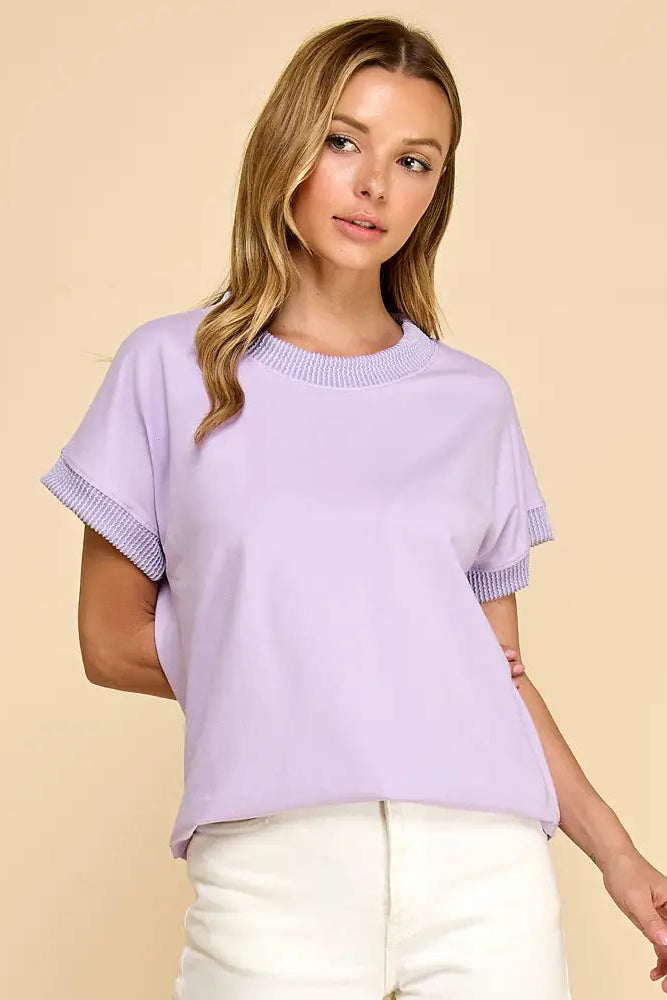 Woman wearing a light purple sweater against a beige background