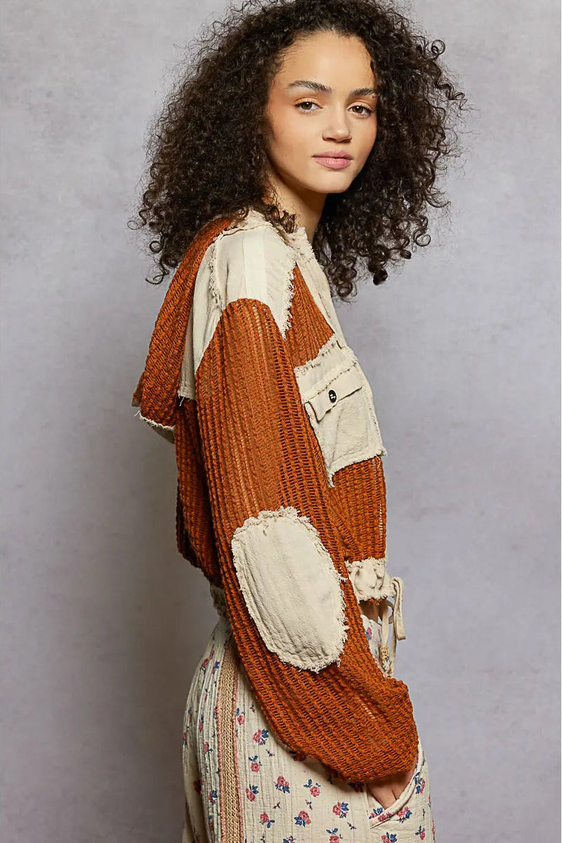 Woman wearing a brown and beige patchwork cardigan against a gray background