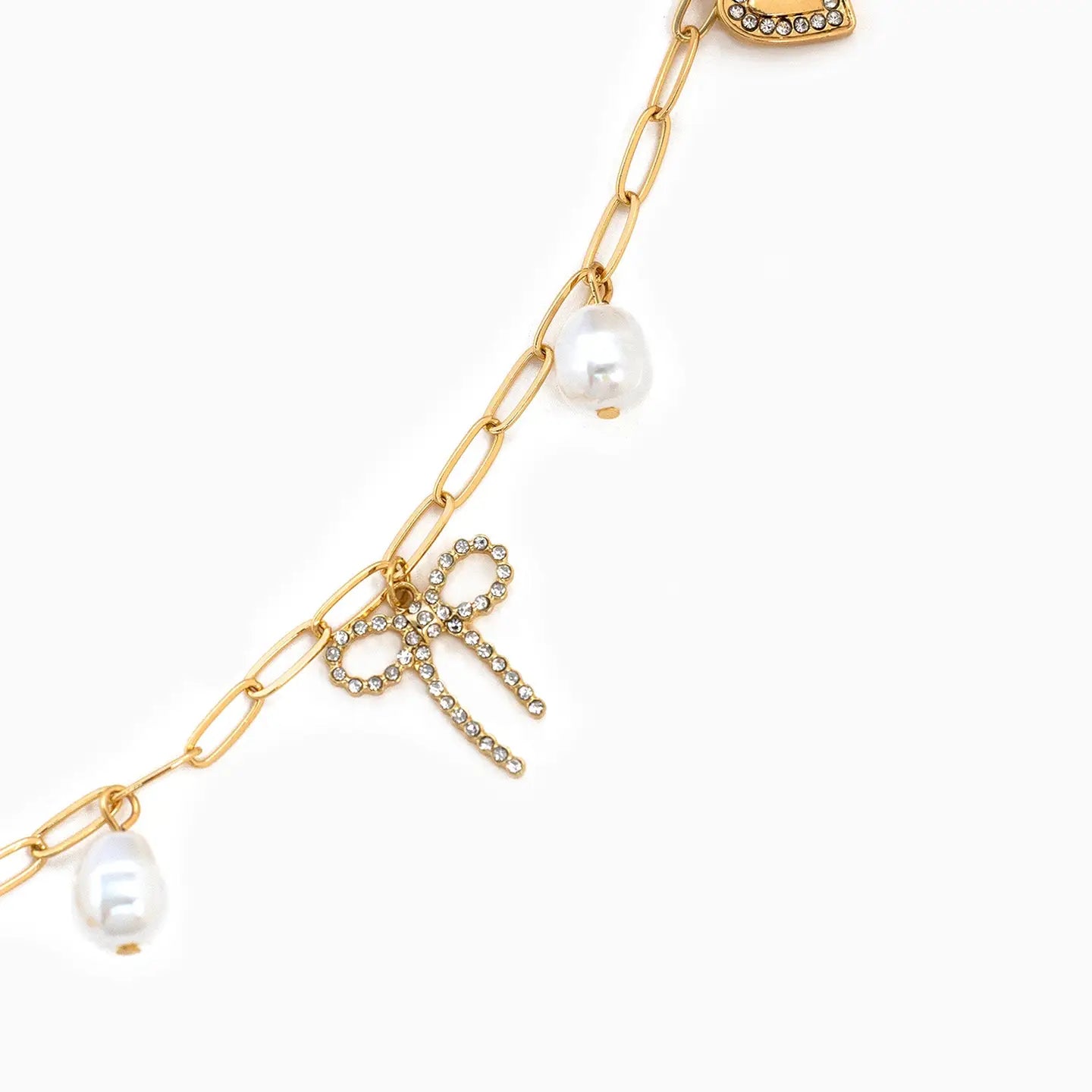 Gold chain necklace with pearl pendants and a bow charm on a white background