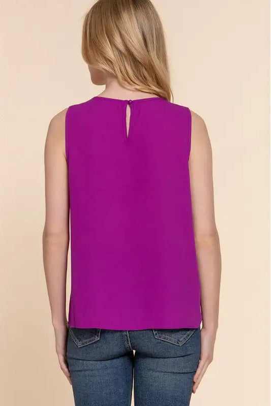 Person wearing a purple sleeveless top on a beige background