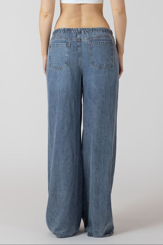 Blue wide-leg jeans worn by a person on a white background