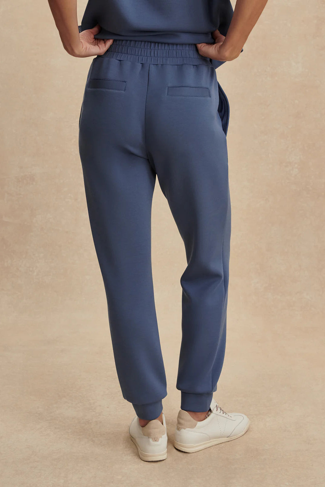 Person wearing blue jogger pants on a beige background