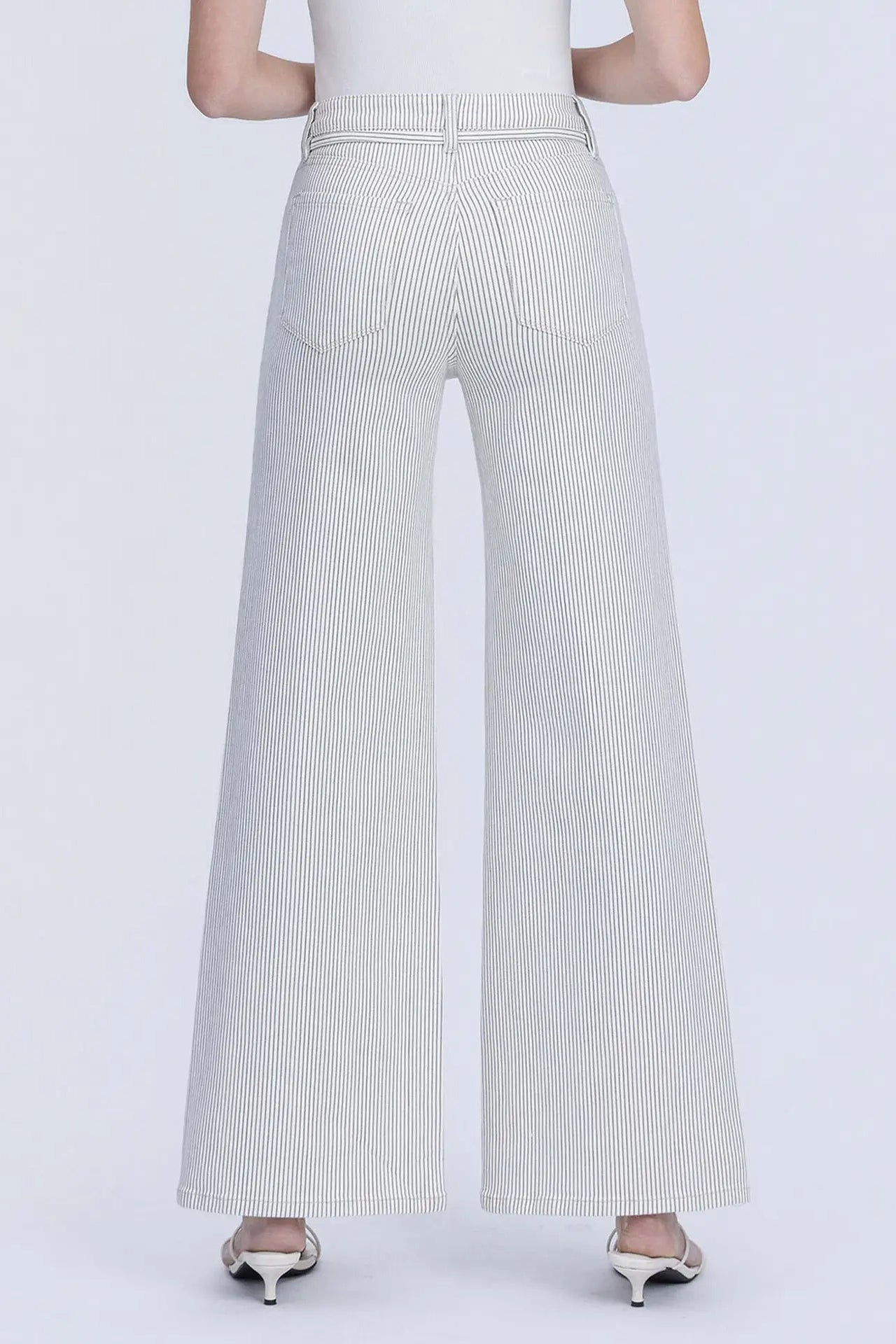 A person shown from the back wearing light gray wide-leg pants with subtle vertical pinstripes, paired with a white top and metallic heels, against a plain light gray studio background.