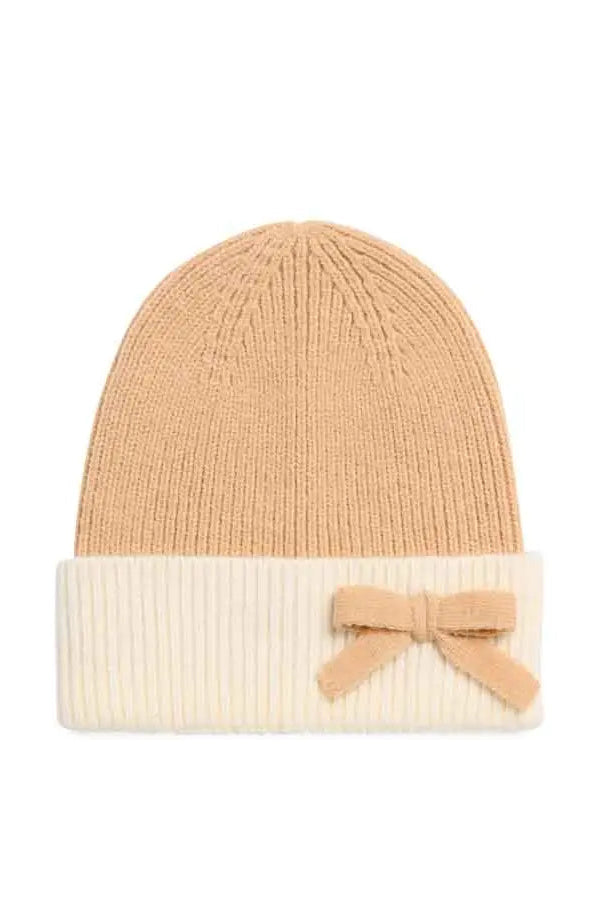 A ribbed knit beanie hat in a warm camel tan color, featuring a contrasting cream-colored folded cuff with a matching tan fabric bow, set against a plain white background.