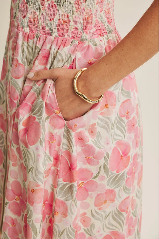 Close-up of a floral dress with pink flowers and green leaves, worn by a person.