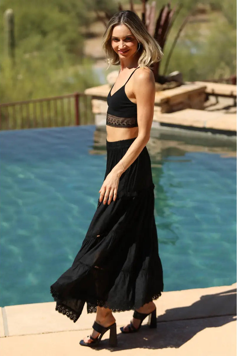 Woman in a black outfit standing by a pool
