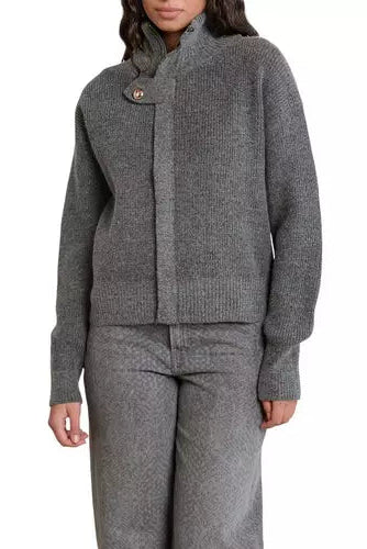 A woman wearing a gray ribbed knit cardigan with a high mock neck and a single decorative button, paired with matching gray knit pants, against a plain white background.