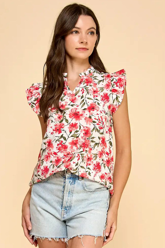 Woman wearing a floral top and denim shorts on a beige background