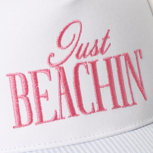 White cap with pink 'Just BEACHIN'' text on a white background