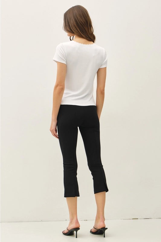 Woman wearing a white t-shirt and black pants on a plain background