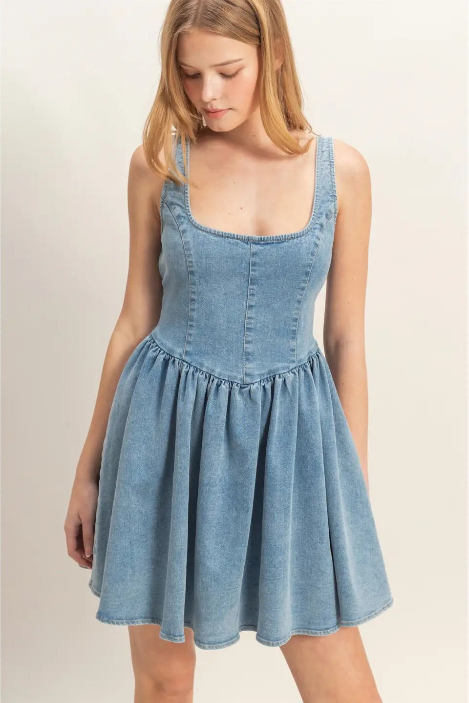 Woman wearing a light blue denim dress against a plain background
