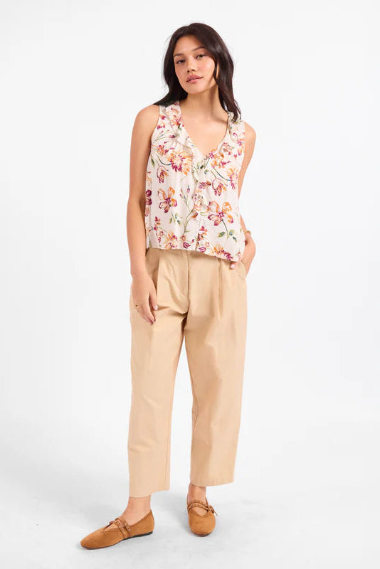 Woman wearing a floral top and beige pants on a white background