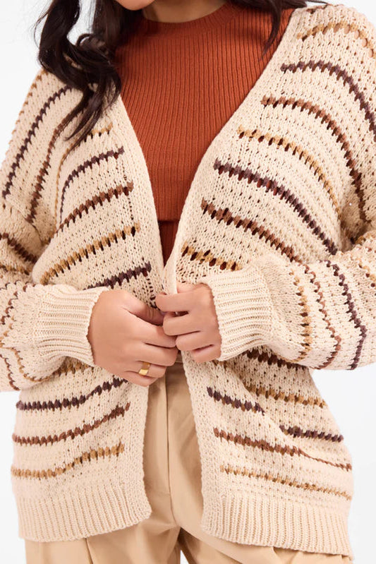 Person wearing a beige and brown striped cardigan on a white background