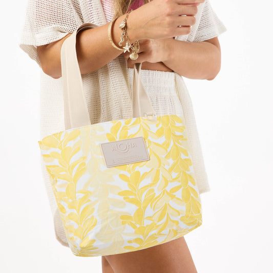 Person holding a yellow and white patterned tote bag with 'Aloha' label.