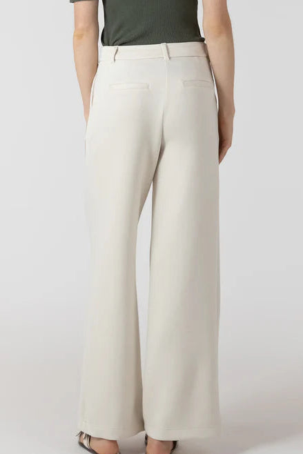 Person wearing beige wide-leg pants and a green top on a white background