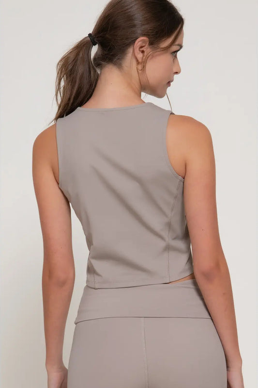 Woman wearing a beige sleeveless top and skirt set on a plain background