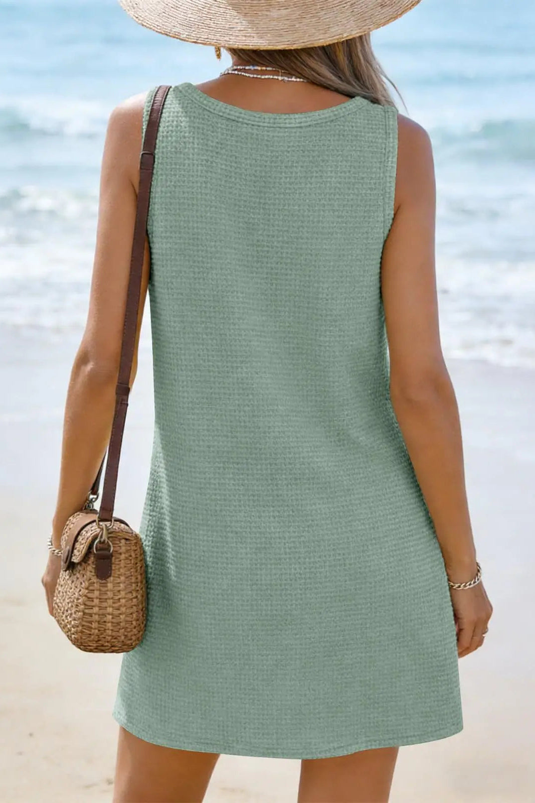 Woman in a green dress standing on a beach with ocean view