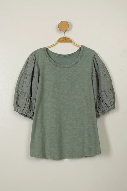 Green dress with puff sleeves on a hanger against a white background