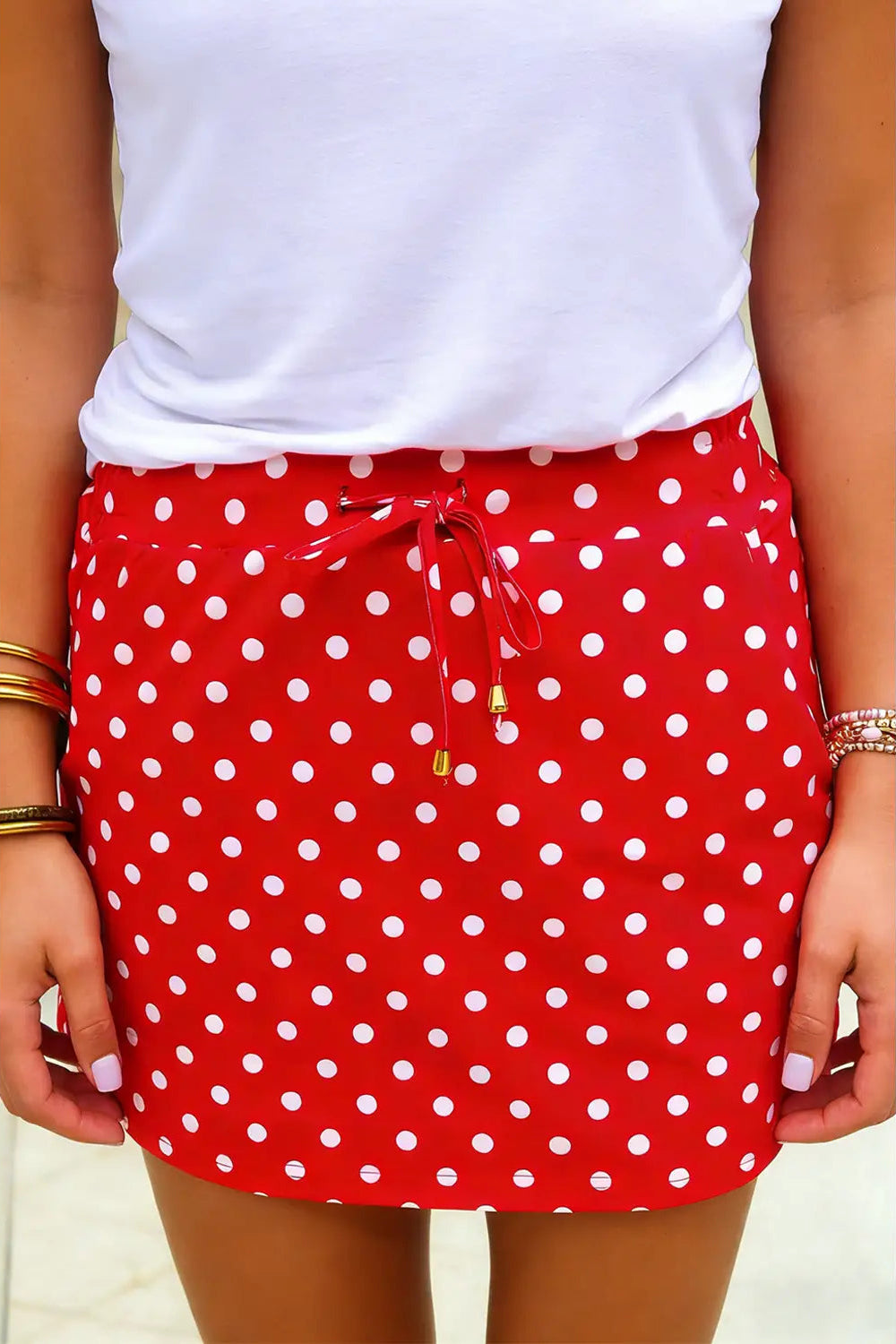 Red polka dot skirt with white top on a neutral background