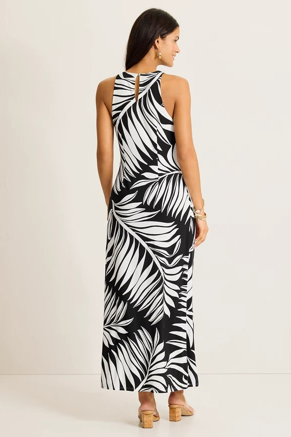 Woman wearing a black and white leaf patterned dress on a plain background