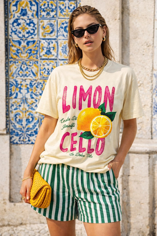 Woman wearing a 'Limon Cello' t-shirt with lemons in front of a colorful tiled wall.