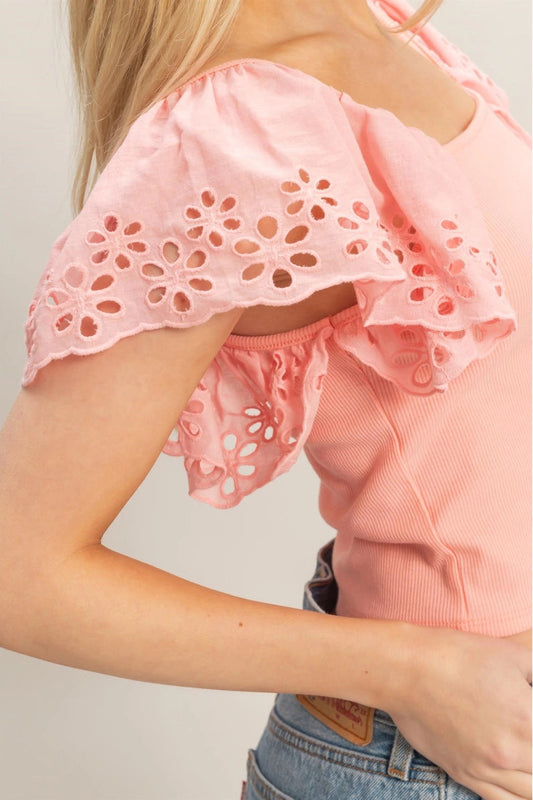 Pink top with cut-out details worn by a person on a plain background