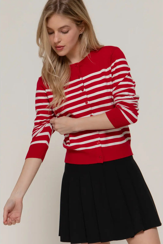 Woman wearing a red and white striped sweater with a black skirt on a plain background