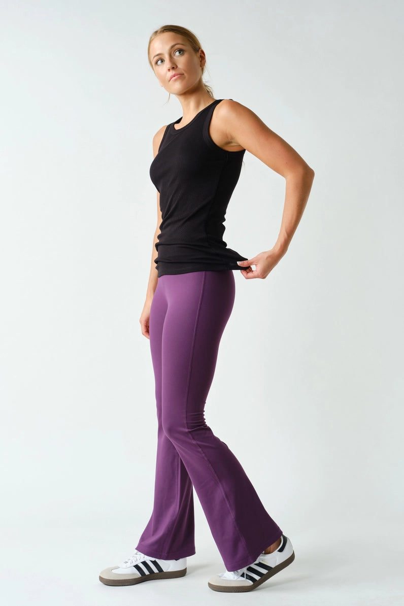 Woman wearing a black tank top and purple pants on a white background