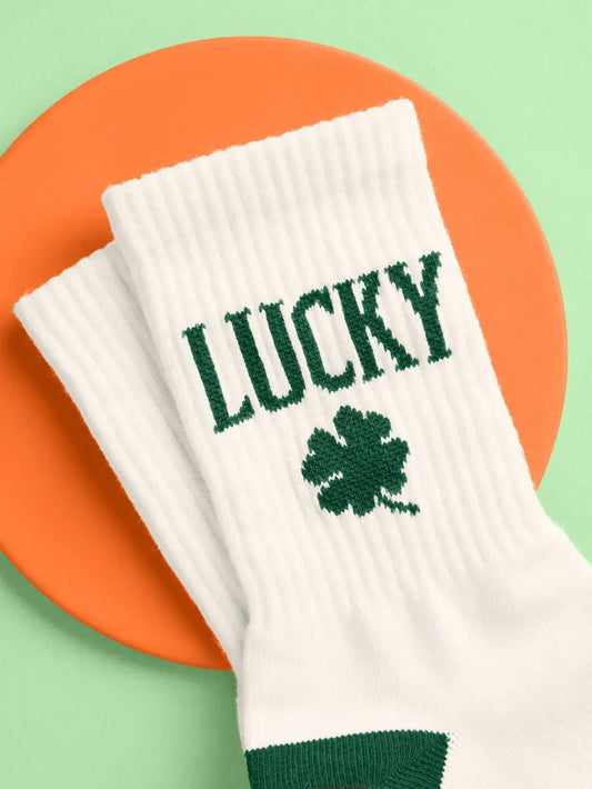 White socks with 'LUCKY' and a clover leaf design on an orange and green background