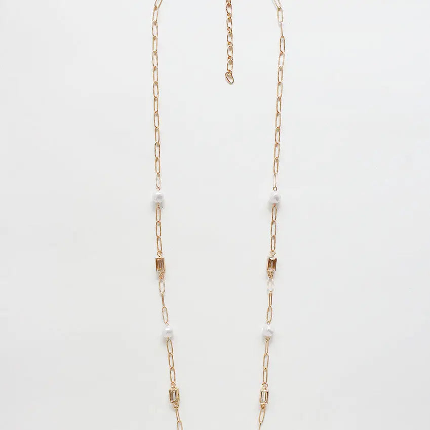 Gold chain necklace with small pearls on a light gray background
