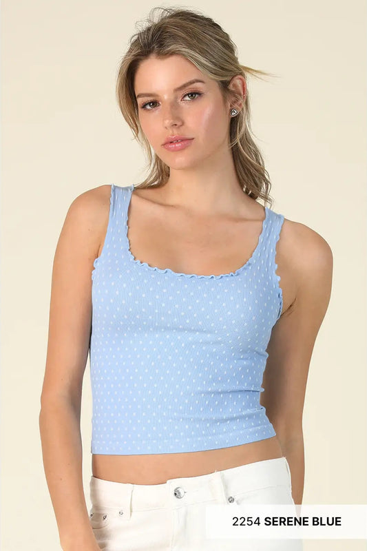 Woman wearing a light blue polka dot crop top against a beige background
