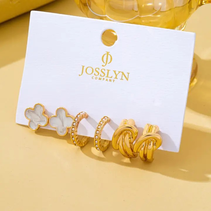 Set of gold earrings on a JOSSLYN Company card against a yellow background