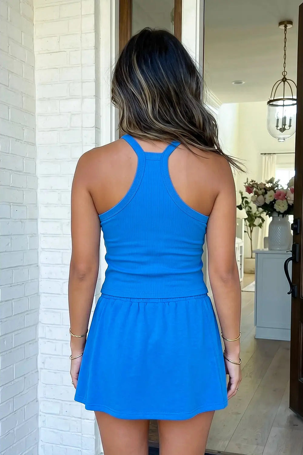 Person wearing a blue dress standing in a room with white walls and a door.