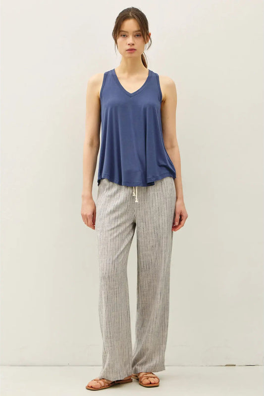 Woman wearing a blue sleeveless top and gray checkered pants on a white background