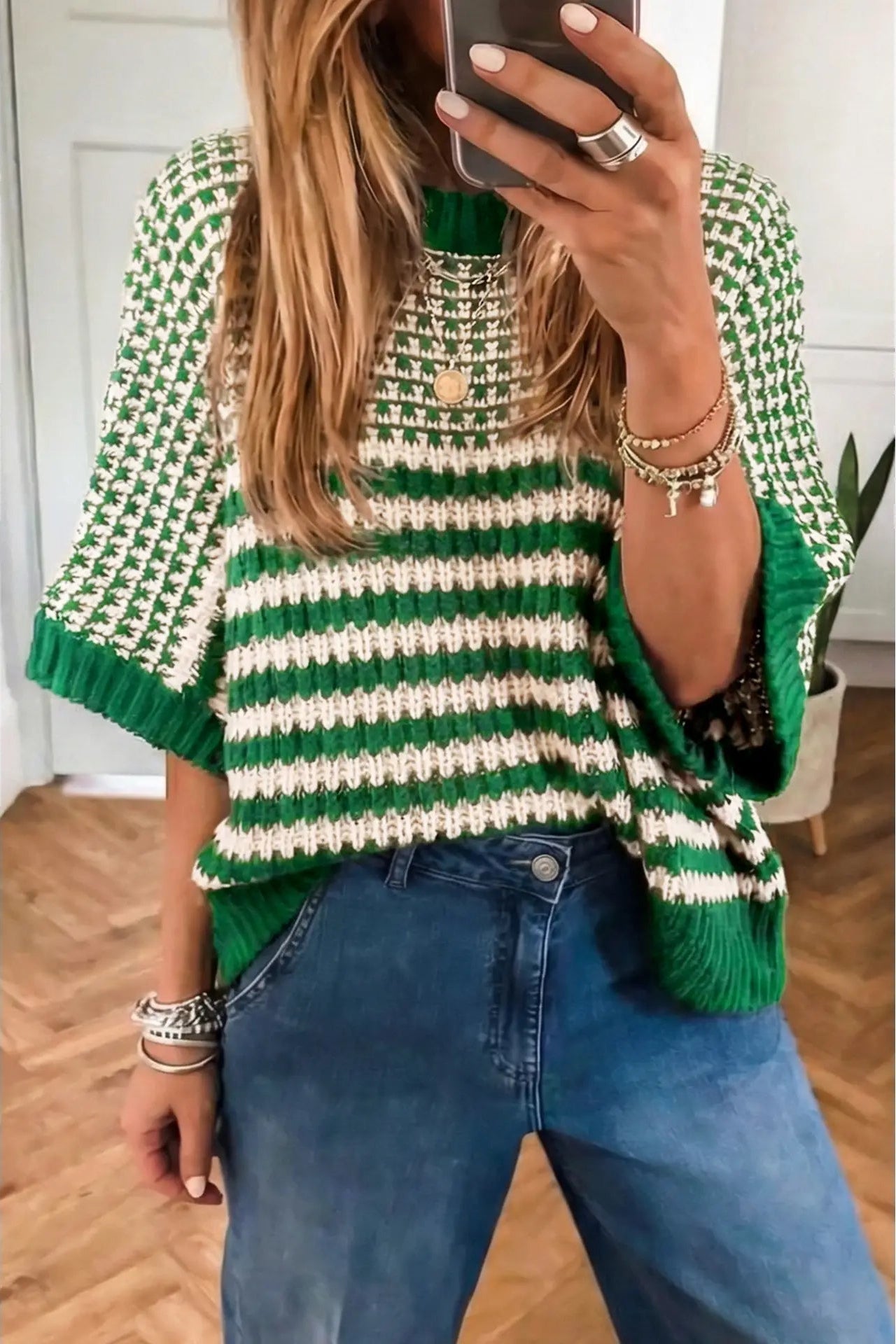 Person wearing a green and white striped sweater taking a mirror selfie.