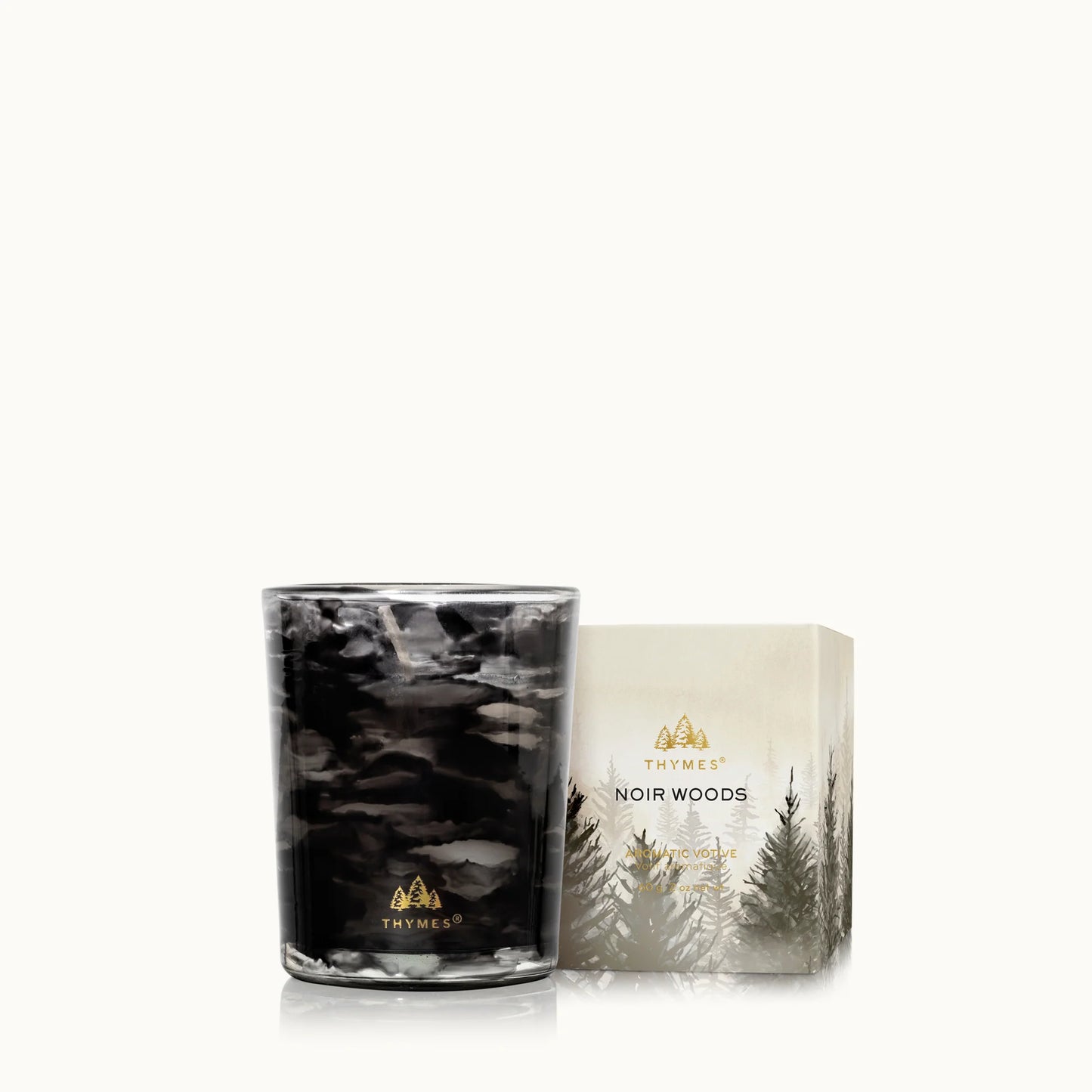 A black and gray marbled glass candle next to its cream-colored packaging box featuring a forest design and gold lettering, set against a plain off-white background.