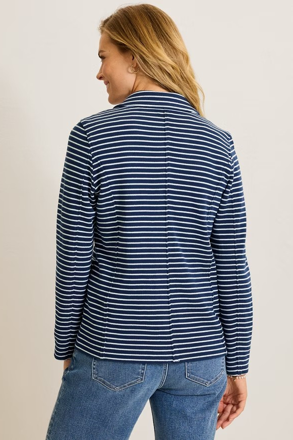 Woman wearing a blue and white striped shirt and jeans on a beige background